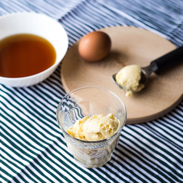 Eggnog ice-cream in a glass with a spoon, an egg and a bowl with Marsala wine
